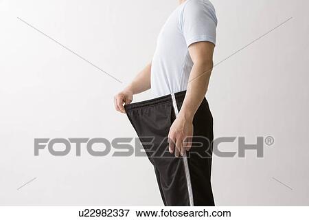 Man pulling pants away from waistline to show weight loss View Large Photo Image Stock Photo - Man pulling pants away from waistline to show weight loss. Fotosearch