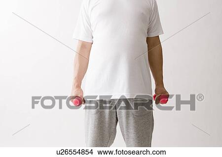 Picture - Mid adult man exercising with dumbbells. Fotosearch