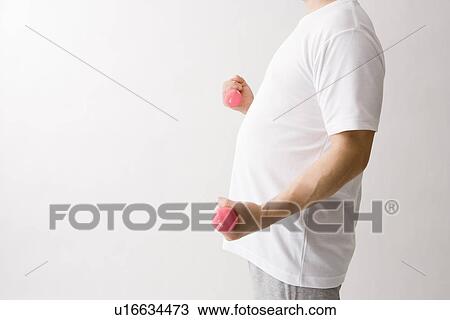 Mid adult man exercising with dumbbells View Large Photo Image Stock Image - Mid adult man exercising with dumbbells. Fotosearch