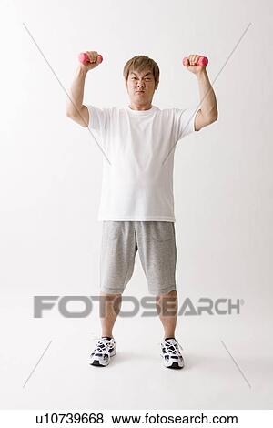 Stock Photo - Mid adult man exercising with dumbbells. Fotosearch