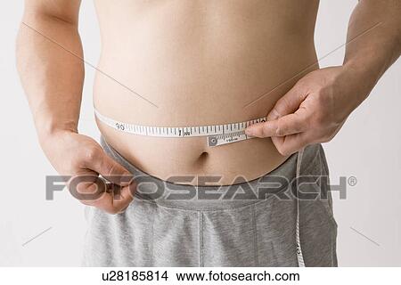 Picture - Mid adult man measuring his waist. Fotosearch