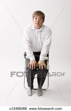 Stock Photograph - Mid adult man sitting. Fotosearch