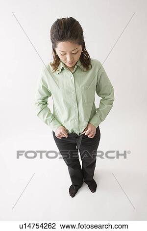Stock Image - Mid adult woman buttoning pants. Fotosearch