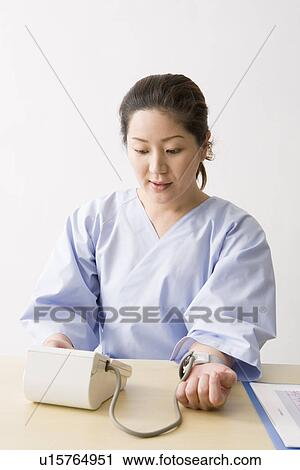 Mid adult woman checking blood pressure View Large Photo Image Stock Image - Mid adult woman checking blood pressure. Fotosearch