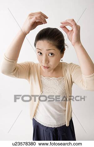 Stock Image - Mid adult woman checking her hair. Fotosearch