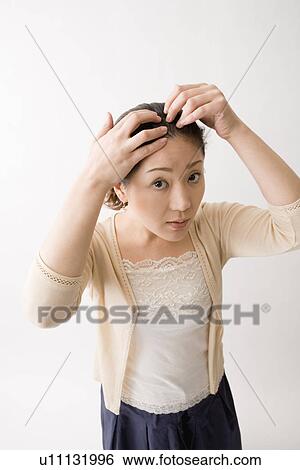 Mid adult woman checking her hair View Large Photo Image Stock Photograph - Mid adult woman checking her hair. Fotosearch