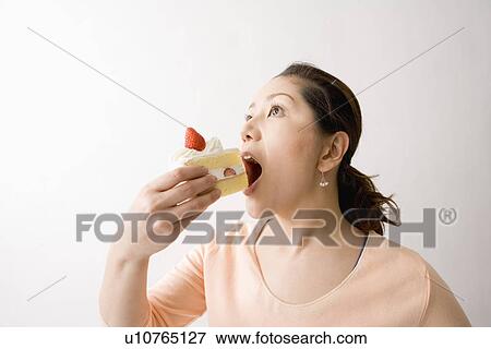Mid adult woman eating cake View Large Photo Image Stock Photo - Mid adult woman eating cake. Fotosearch