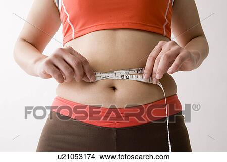 Picture - Mid adult woman measuring her waist. Fotosearch