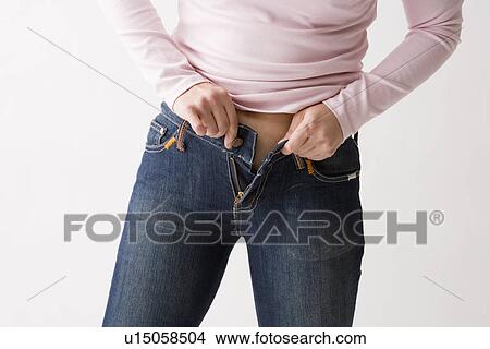 Picture - Mid adult woman putting on jeans. Fotosearch