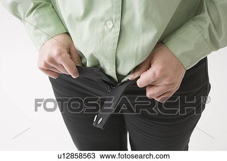 Stock Image - Mid adult woman putting on pants. Fotosearch