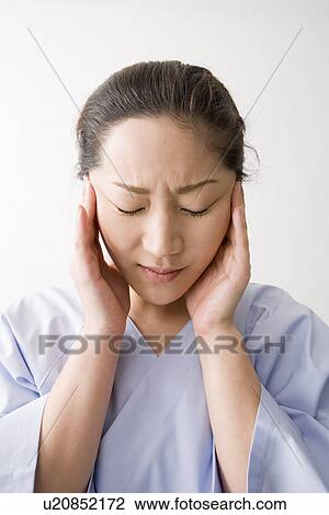 Stock Image - Mid adult woman suffering from headache. Fotosearch