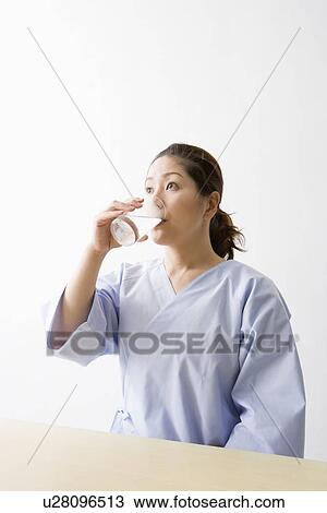 Stock Image - Mid adult woman taking pills. Fotosearch