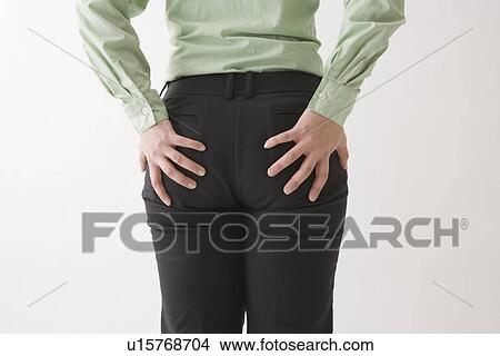 Picture - Mid adult woman touching her buttocks. Fotosearch