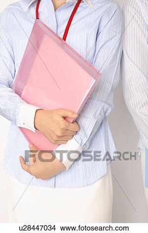 Upper part of body of woman holding a file View Large Photo Image Picture - Upper part of body of woman holding a file. Fotosearch