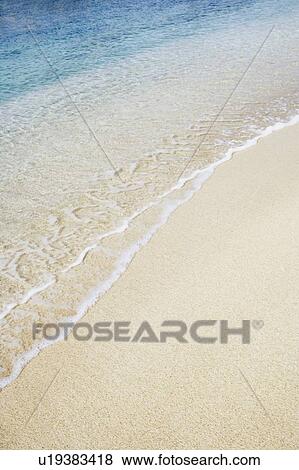 Stock Photo - High angle view of waves breaking on the beach. Fotosearch