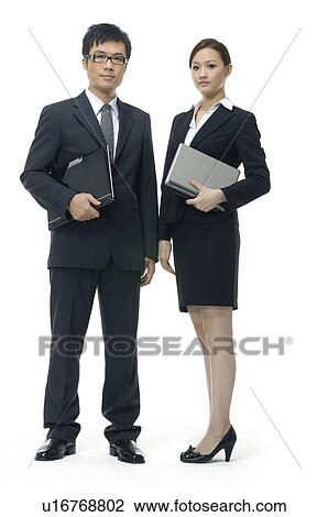 Stock Image - Businessman and a businesswoman holding laptops. Fotosearch
