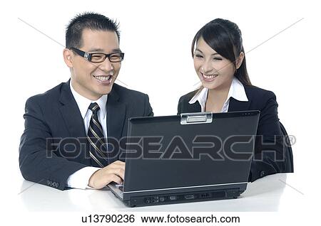 Businessman and a businesswoman working on a laptop View Large Photo Image Stock Photograph - Businessman and a businesswoman working on a laptop. Fotosearch