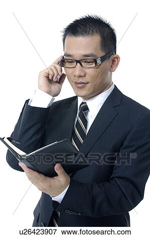Businessman holding a planner and talking on a mobile phone View Large Photo Image Stock Photo - Businessman holding a planner and talking on a mobile phone. Fotosearch