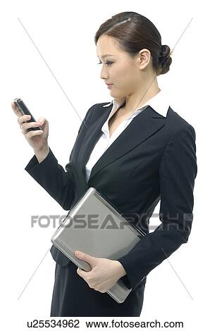 Businesswoman holding a laptop and looking at a mobile phone View Large Photo Image Stock Image - Businesswoman holding a laptop and looking at a mobile phone. Fotosearch