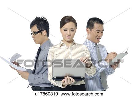 Stock Photo - Businesswoman looking at a laptop and two businessmen doing paperwork. Fotosearch