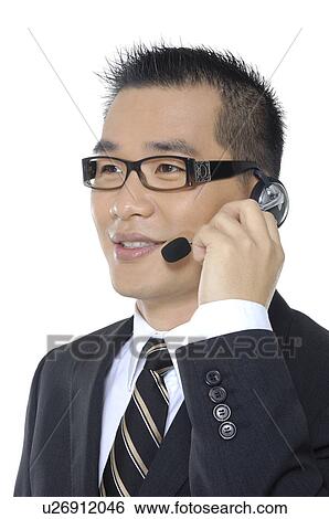 Stock Photograph - Close-up of a male customer care executive adjusting his headset. Fotosearch