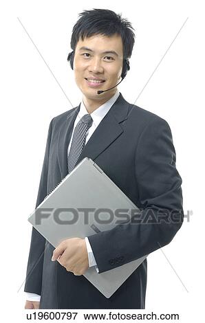 Stock Photo - Portrait of a businessman holding a laptop and wearing a headset. Fotosearch