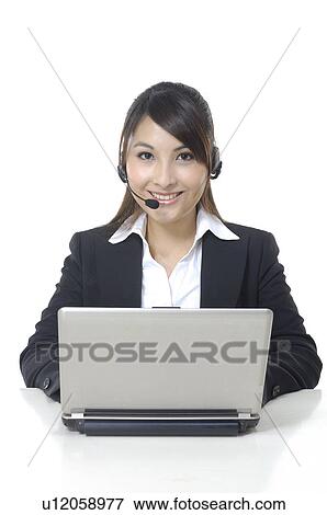 Portrait of a businesswoman working on a laptop and wearing a headset View Large Photo Image Stock Photo - Portrait of a businesswoman working on a laptop and wearing a headset. Fotosearch