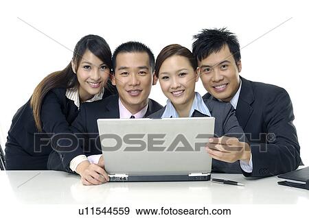 Two businessmen and two businesswomen working on a laptop View Large Photo Image Stock Photo - Two businessmen and two businesswomen working on a laptop. Fotosearch