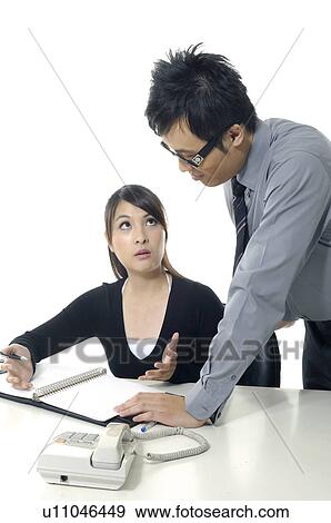 Stock Photo - Businessman and a businesswoman discussing a document. Fotosearch