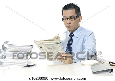 Businessman reading a financial newspaper and holding a tea cup View Large Photo Image Stock Image - Businessman reading a financial newspaper and holding a tea cup. Fotosearch