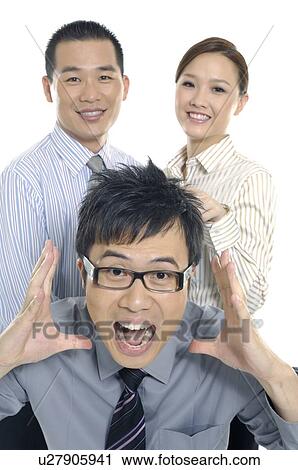 Stock Image - Businessman shouting with his colleagues smiling behind him. Fotosearch