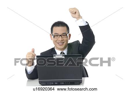 Picture - Businessman working on a laptop and raising his hands. Fotosearch