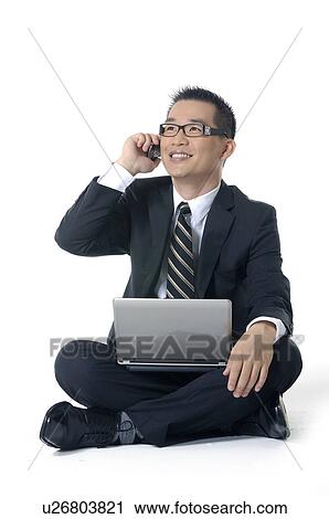 Businessman working on a laptop and talking on a mobile Phone View Large Photo Image Stock Image - Businessman working on a laptop and talking on a mobile Phone. Fotosearch