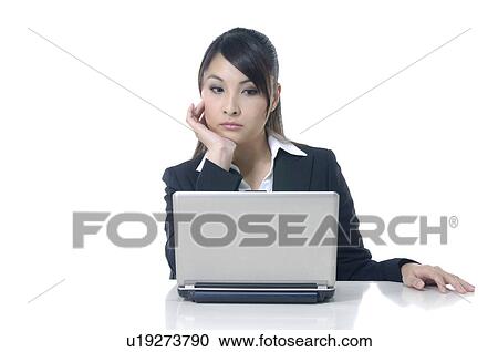 Stock Image - Pensive businesswoman looking at a laptop. Fotosearch