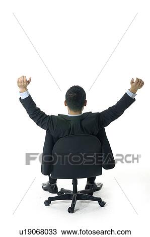 Stock Image - Rear view of a businessman relaxing with his hands raised. Fotosearch