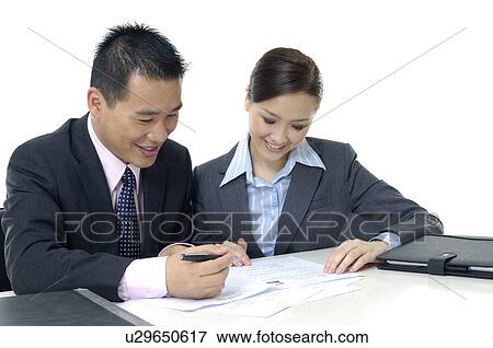 Businessman and a businesswoman discussing a document View Large Photo Image Stock Photo - Businessman and a businesswoman discussing a document. Fotosearch