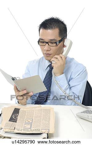 Businessman looking at a personal diary and talking on a landline phone View Large Photo Image Stock Image - Businessman looking at a personal diary and talking on a landline phone. Fotosearch