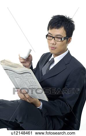 Stock Image - Businessman reading a financial newspaper and holding a tea cup. Fotosearch