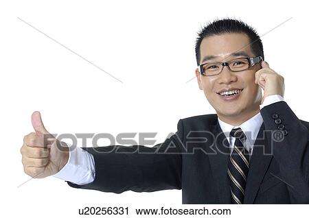 Stock Image - Businessman talking on a mobile phone and showing thumbs up. Fotosearch