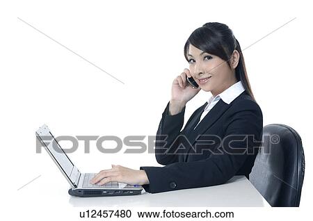 Businesswoman working on a laptop and talking on a mobile Phone View Large Photo Image Stock Image - Businesswoman working on a laptop and talking on a mobile Phone. Fotosearch
