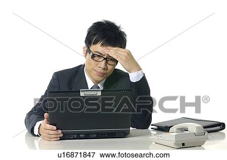 Depressed businessman looking at a laptop View Large Photo Image Stock Photo - Depressed businessman looking at a laptop. Fotosearch