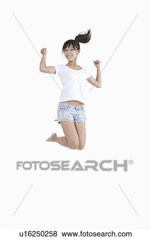 Young girl jumping in mid-air with arms outstretched and smiling happily View Large Photo Image Stock Photo - Young girl jumping in mid-air with arms outstretched and smiling happily. Fotosearch