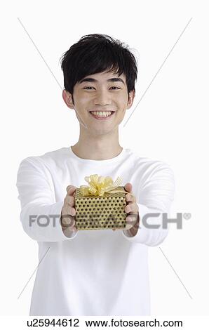 Young man giving a gift with smile View Large Photo Image Stock Image - Young man giving a gift with smile. Fotosearch