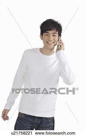 Young man holding mobile phone and smiling happily View Large Photo Image Stock Image - Young man holding mobile phone and smiling happily. Fotosearch