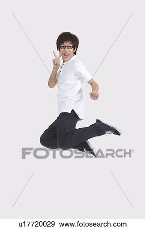 Young man jumping in mid-air and sticking out tongue with smile View Large Photo Image Stock Photo - Young man jumping in mid-air and sticking out tongue with smile. Fotosearch