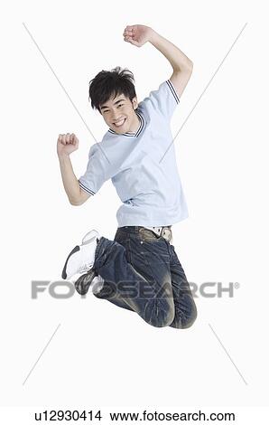 Picture - Young man jumping in mid-air with arms outstretched and smiling with excitement. Fotosearch