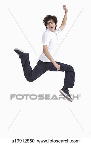 Stock Image - Young man jumping in mid-air with mouth open and smiling. Fotosearch