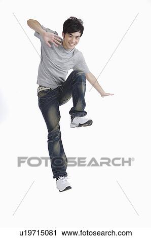 Stock Image - Young man jumping with arms outstretched and smiling. Fotosearch