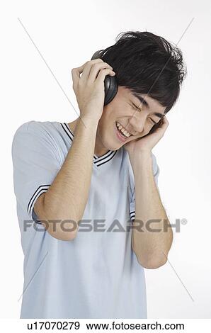 Young man listening music with headset and smiling happily with eyes closed View Large Photo Image Stock Photo - Young man listening music with headset and smiling happily with eyes closed. Fotosearch