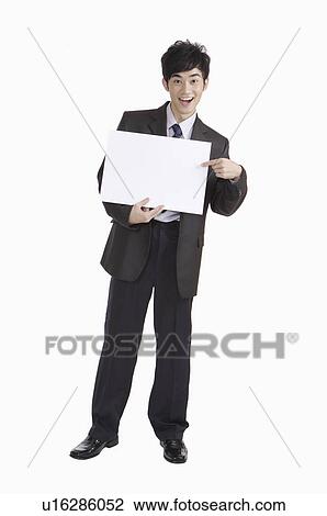 Young man pointing at a paper and smiling View Large Photo Image Stock Image - Young man pointing at a paper and smiling. Fotosearch
